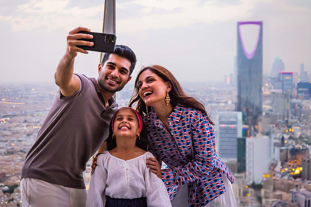 Une famille se prend en photo (selfie) devant la ville de Riyad.